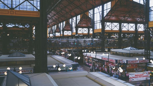 부다페스트 그레이트 마켓 홀, 웅장한 철제 지붕 아래 활기찬 상점들과 방문객들이 어우러진 전통 시장의 내부 전경입니다.