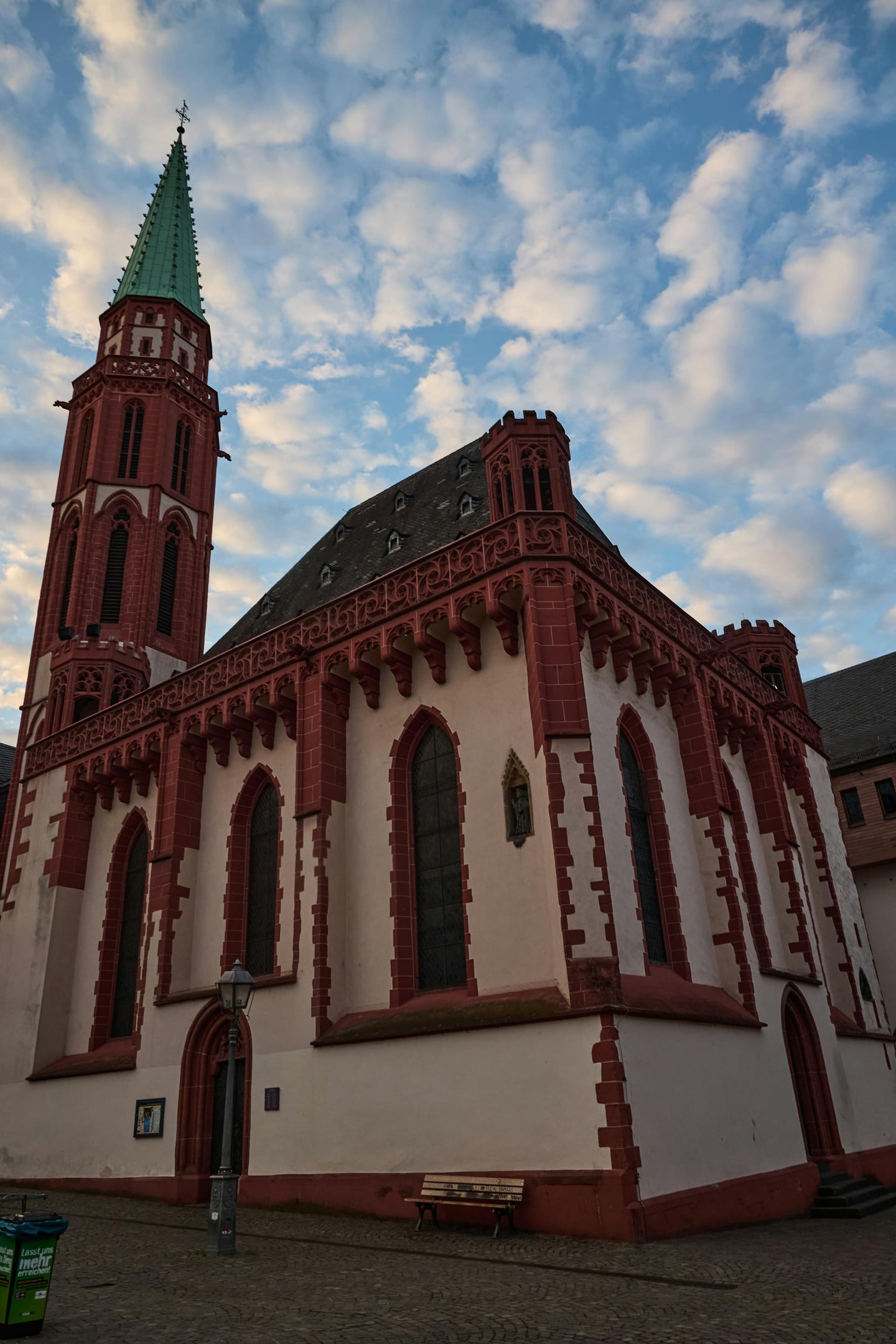 프랑크푸르트 니콜라이 교회, 푸른 하늘 아래 붉은 사암 장식과 고딕 양식의 첨탑이 돋보이는 역사적인 건축물 외관입니다.