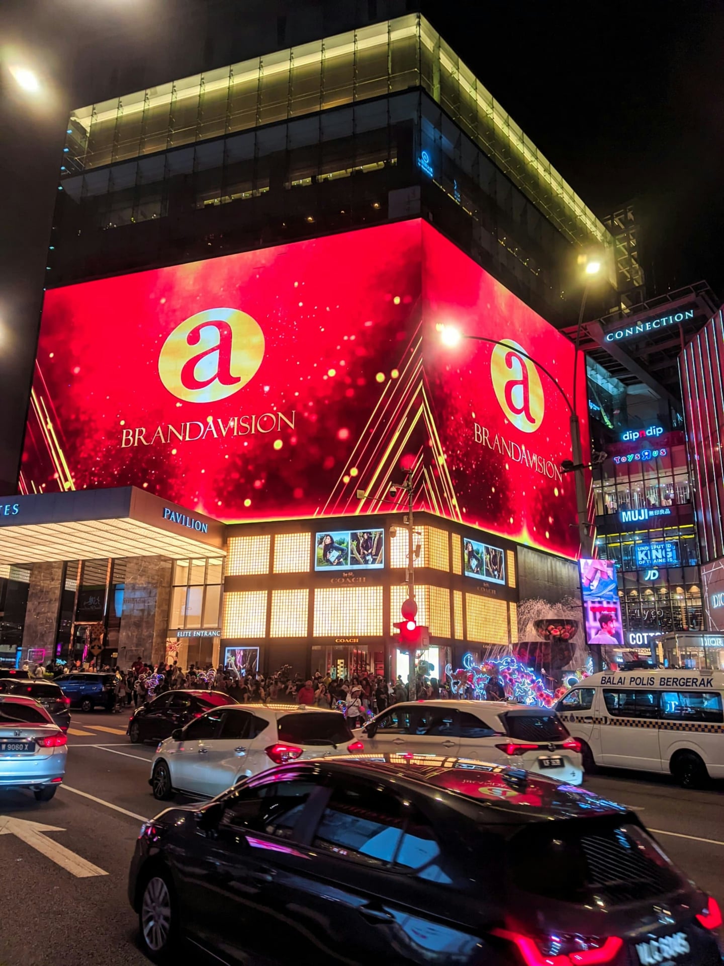 쿠알라룸푸르 파빌리온, 화려한 붉은색 대형 전광판과 활기찬 도심의 밤거리가 어우러진 쇼핑몰 외관입니다.
