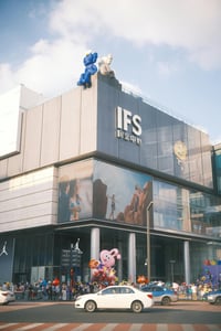 청두 IFS 거리, 카우스 조형물이 설치된 현대적인 쇼핑몰 외관과 활기찬 도심의 횡단보도 풍경이 조화를 이룹니다.