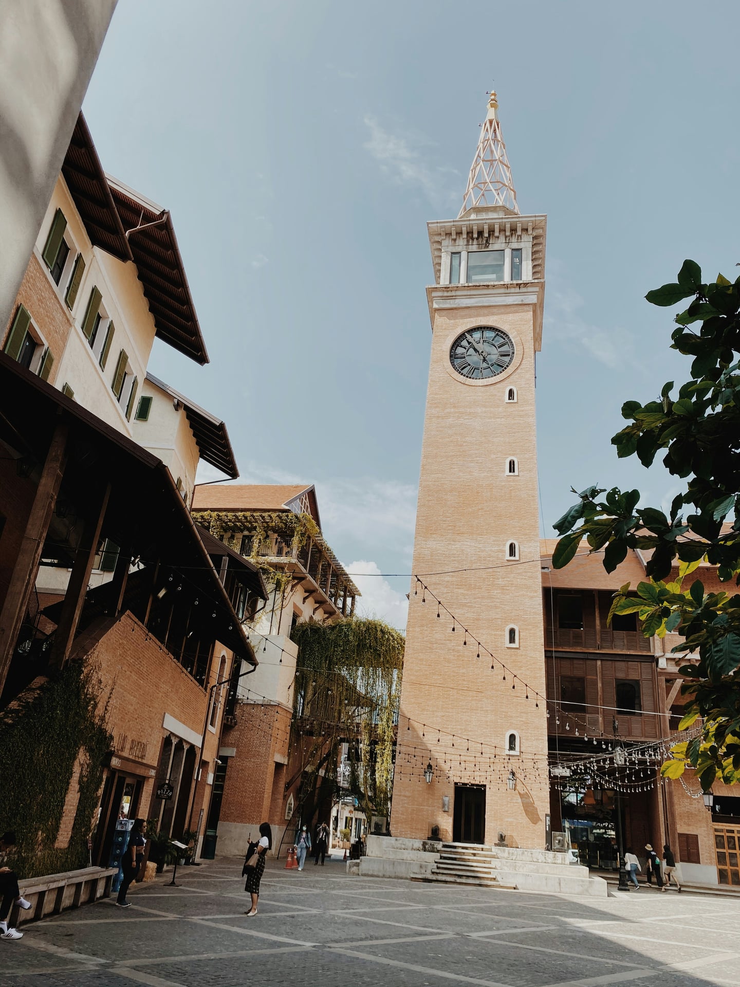 치앙마이 원 님만, 푸른 하늘 아래 우뚝 솟은 고풍스러운 시계탑과 유럽 스타일의 붉은 벽돌 건물이 자아내는 이국적인 광장 전경입니다.