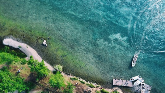 홉스골 홉스골, 투명한 에메랄드빛 호수 위로 하얀 보트가 가로지르며 선착장 주변의 평화로운 자연 풍경을 담고 있습니다.