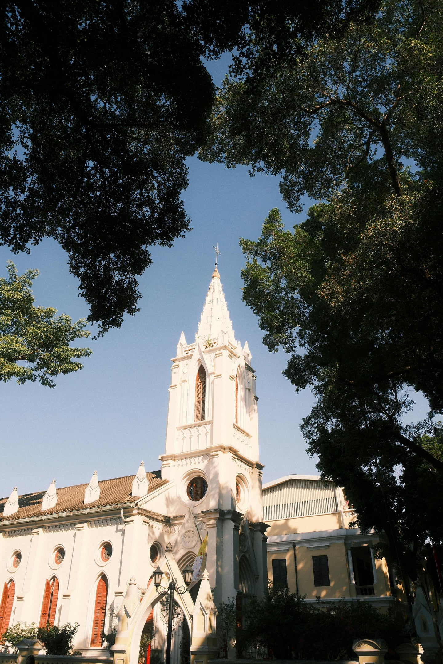 광저우 사면도, 울창한 나무들 사이로 솟아오른 루르드 성모 성당의 하얀 고딕 양식 첨탑과 고풍스러운 외관이 돋보이는 풍경입니다.