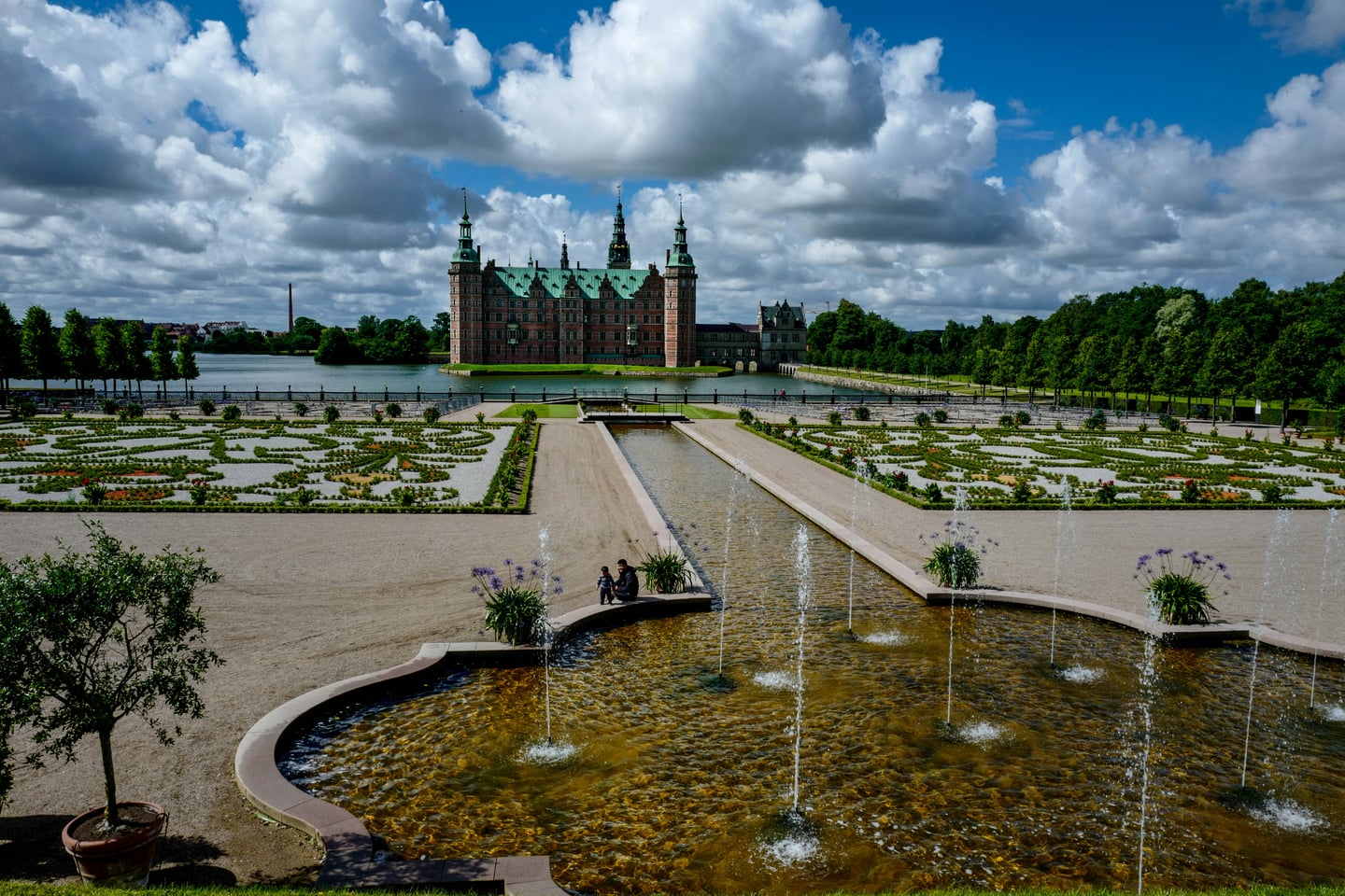 힐레뢰드 프레데릭스보르 성, 화려한 바로크 정원의 분수 너머로 호수 위에 솟아오른 웅장한 르네상스 양식의 성곽 풍경입니다.