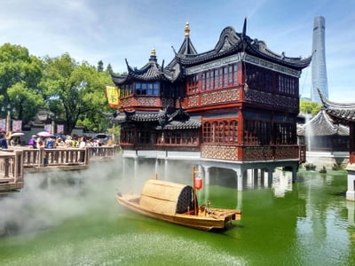 상하이 나룻배 유람, 예원 호심정의 고풍스러운 목조 건물과 물안개 낀 연못 위를 유유히 떠다니는 전통 나룻배의 평화로운 전경입니다.