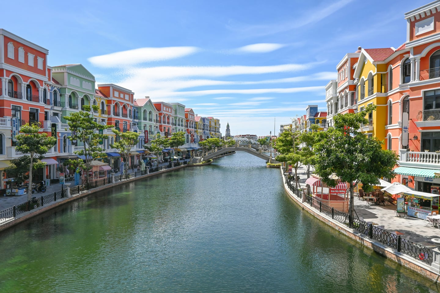 푸꾸옥 그랜드 월드, 맑은 하늘 아래 운하를 따라 펼쳐진 화려한 원색의 유럽풍 건물들과 평화로운 수로 풍경입니다.
