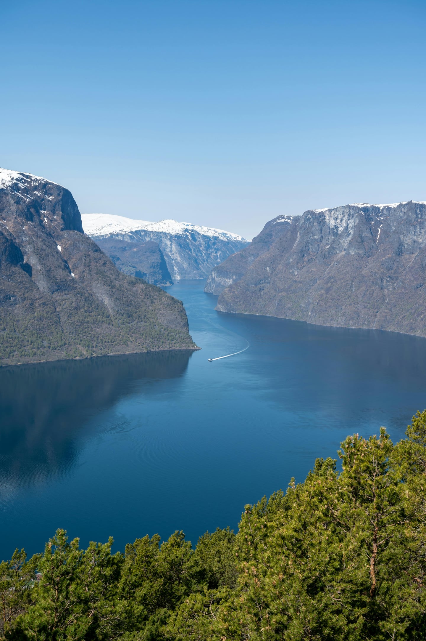 오슬로 송네 피오르드, 깎아지른 듯한 절벽 사이로 펼쳐진 푸른 바닷길과 멀리 보이는 설산이 어우러진 웅장한 대자연의 풍경입니다.
