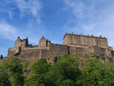 에든버러 에든버러 성, 푸른 하늘 아래 깎아지른 듯한 바위 절벽 위에 세워진 고성 유적의 웅장하고 견고한 석조 외관입니다.