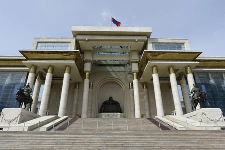 울란바토르 몽골 정부청사, 웅장한 흰색 기둥 사이로 칭기즈 칸 동상이 위엄 있게 자리 잡은 국회의사당 정면의 모습입니다.