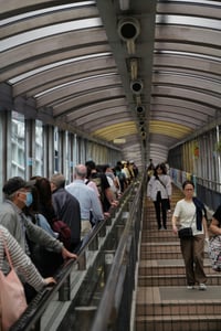 홍콩 미드레벨 에스컬레이터, 투명한 돔 형태의 지붕 아래 에스컬레이터를 타고 이동하는 관광객들과 현지인들의 활기찬 일상 풍경입니다.