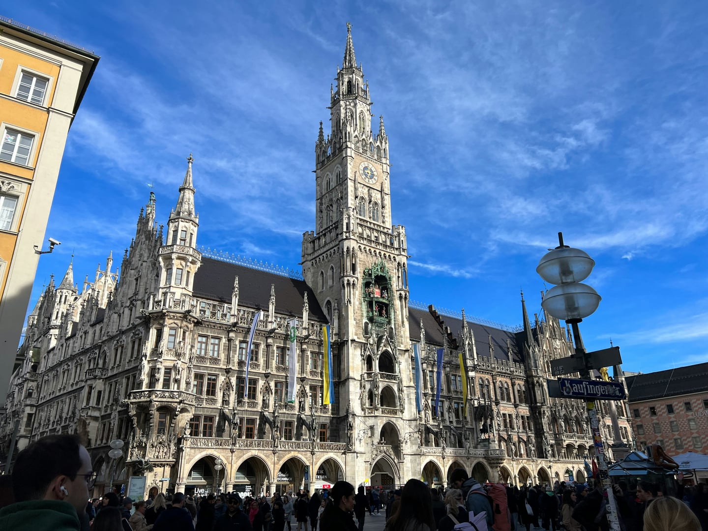 뮌헨 신 시청사, 푸른 하늘 아래 마리엔 광장을 압도하는 웅장한 네오고딕 양식의 석조 건물과 정교한 시계탑의 모습입니다.