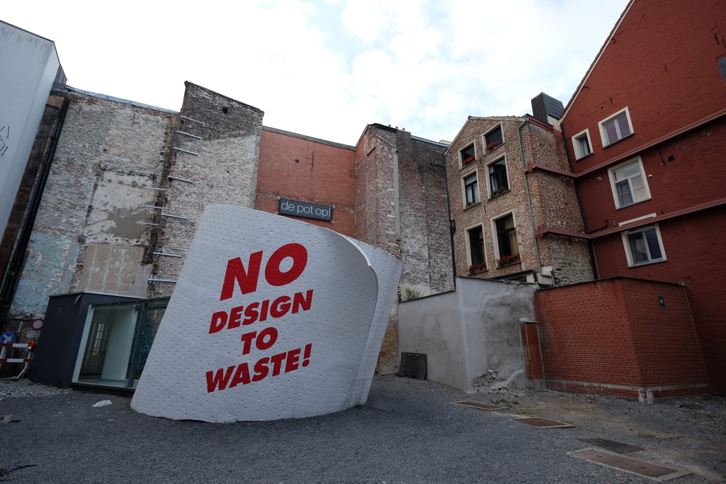 겐트 겐트 디자인 박물관, 야외 광장에 설치된 'NO DESIGN TO WASTE!' 문구의 거대한 휴지 조형물과 붉은 벽돌 건물의 조화.