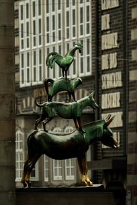 브레멘 브레멘 음악대, 고풍스러운 건물 배경 앞에 당나귀와 개, 고양이, 수탉이 층층이 쌓인 청동상이 위엄 있게 서 있습니다.