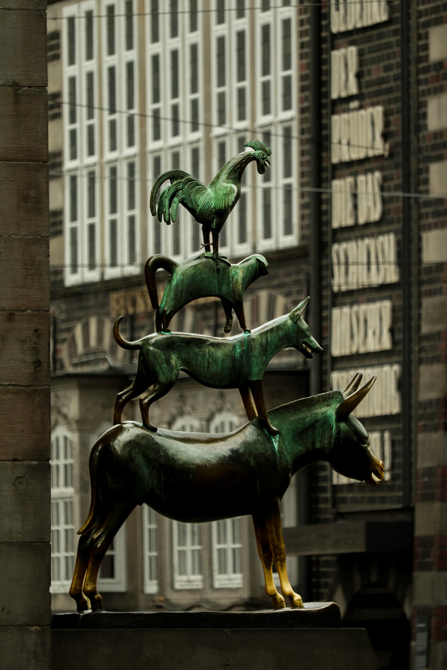 브레멘 브레멘 음악대, 고풍스러운 건물 배경 앞에 당나귀와 개, 고양이, 수탉이 층층이 쌓인 청동상이 위엄 있게 서 있습니다.