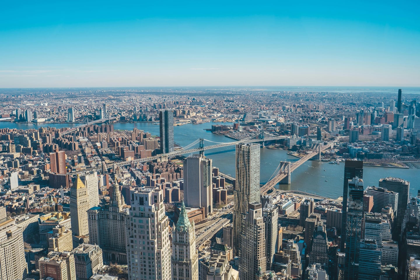 뉴욕 원월드 트레이드센터 전망대, 이스트 강 위로 브루클린 브릿지와 맨해튼 브릿지가 나란히 펼쳐진 웅장한 도시 전경입니다.