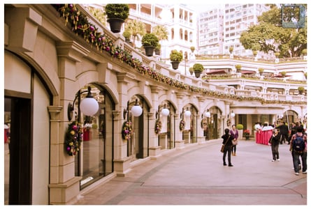 홍콩 1881 헤리티지, 고전적인 유럽풍 석조 아치 건물과 화려한 크리스마스 리스 장식이 어우러진 광장 풍경입니다.