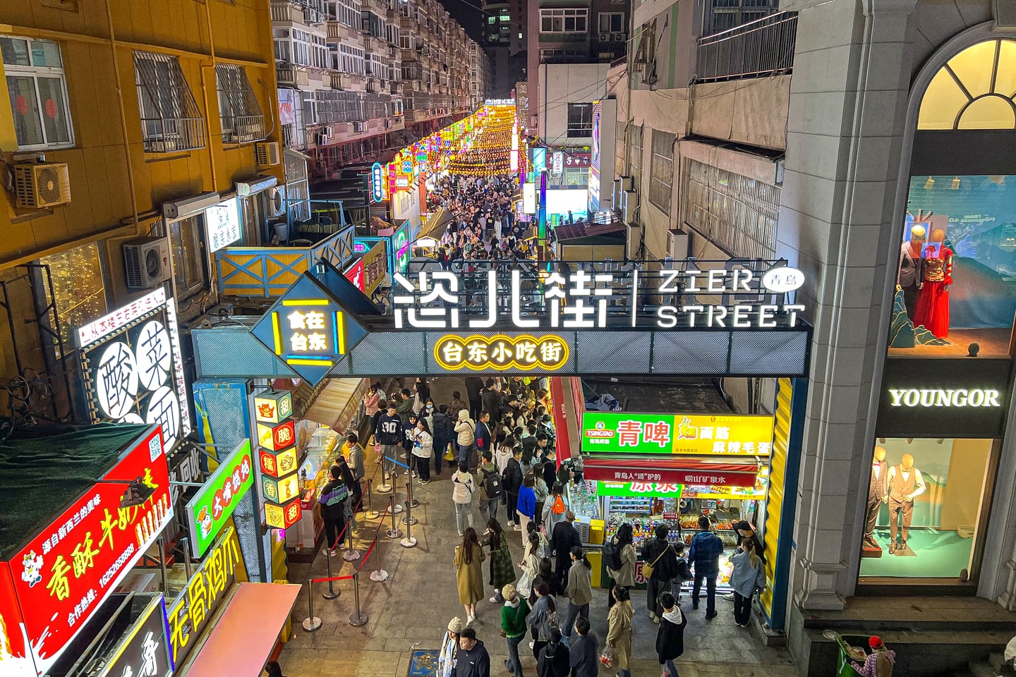 칭다오 타이동 야시장, 화려한 네온사인 간판과 수많은 인파가 어우러진 활기찬 먹거리 골목의 밤 풍경입니다.