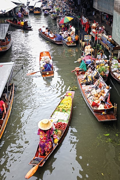 방콕 담넌사두억 수상시장, 알록달록한 열대 과일과 기념품을 가득 실은 전통 배들이 수로 위에서 활기차게 거래하는 풍경입니다.