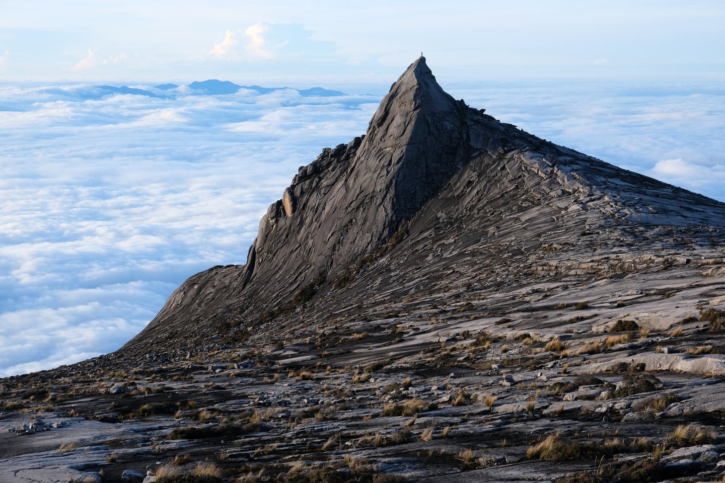 코타키나발루 키나발루 산, 구름 바다 위로 웅장하게 솟아오른 날카로운 화강암 봉우리와 거친 암벽의 장엄한 풍경입니다.