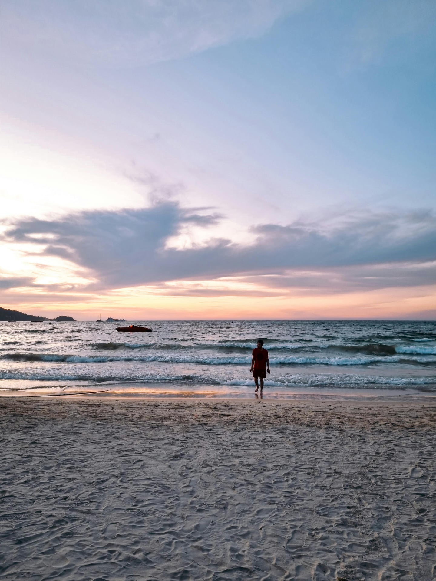 푸켓 파통 비치, 노을이 지는 해변에서 파도를 맞으며 여유로운 시간을 보내는 여행객과 아름다운 바다 풍경입니다.
