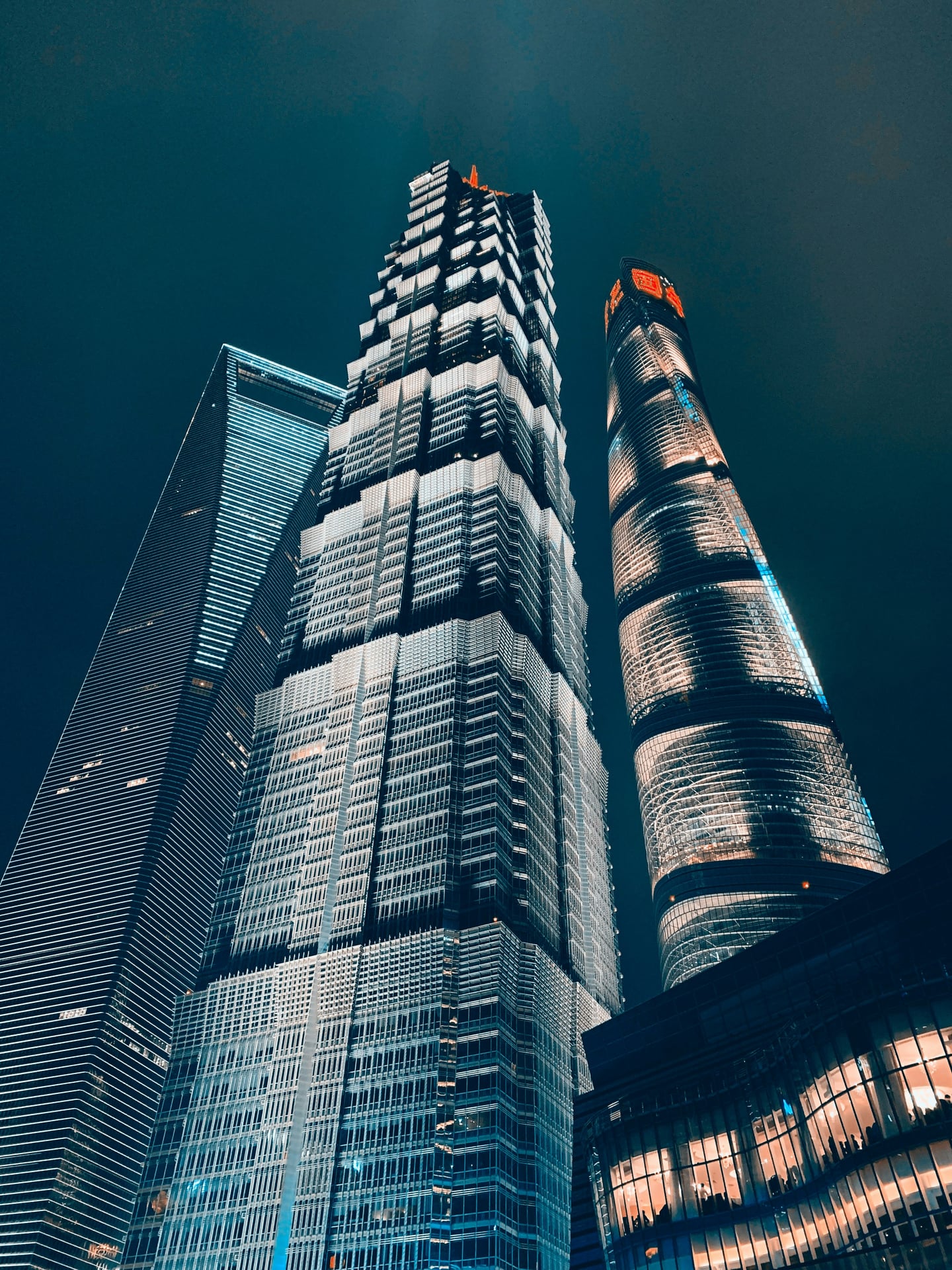 상하이 진마오 타워, 밤하늘을 배경으로 화려한 조명이 빛나는 초고층 빌딩들의 웅장한 수직적 야경 모습입니다.