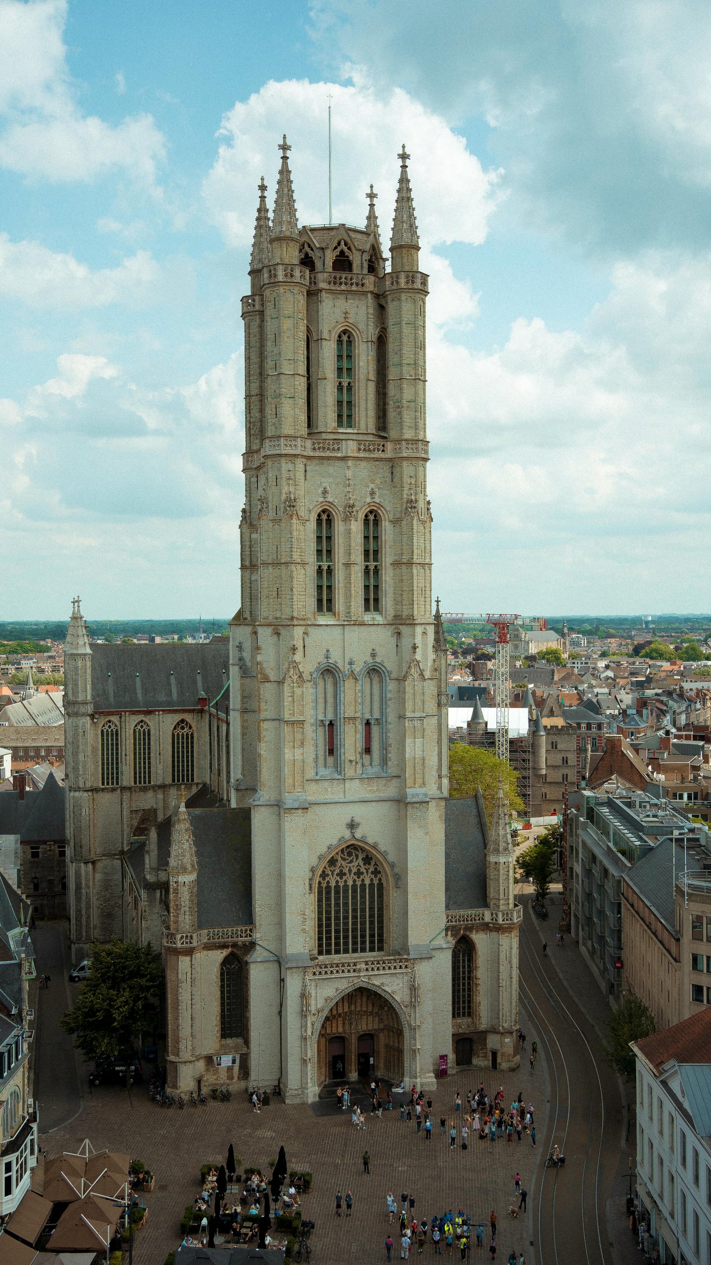 겐트 성 바보 성당, 푸른 하늘 아래 우뚝 솟은 고딕 양식의 거대한 종탑과 광장을 가득 메운 사람들의 활기찬 모습.